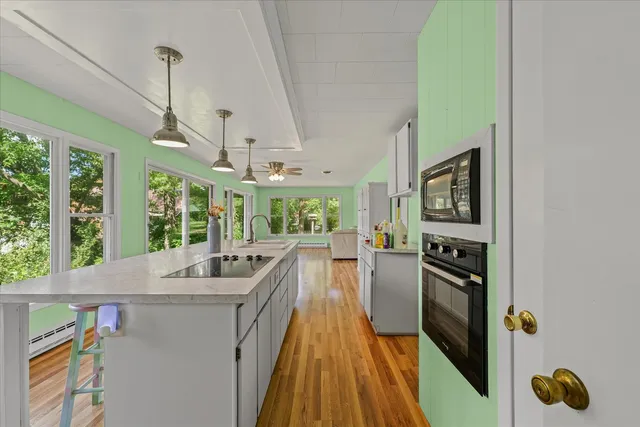 a kitchen with stainless steel appliances granite countertop a kitchen island a stove and a wooden floors
