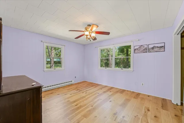 a view of room with wooden floor and a ceiling fan