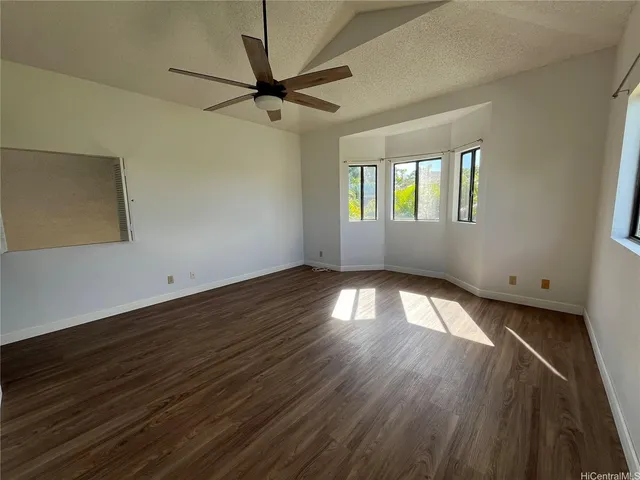 an empty room with wooden floor fan and windows