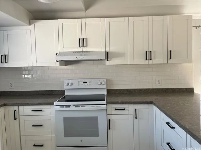 a kitchen with granite countertop white cabinets and white appliances