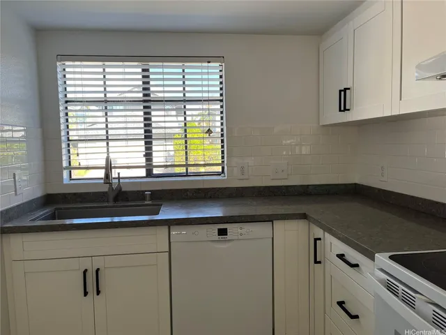 a kitchen with granite countertop white cabinets and a window