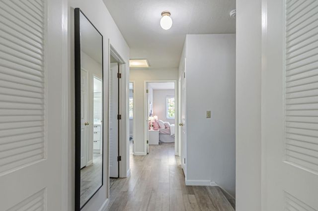 a view of a hallway with wooden floor and a bathroom