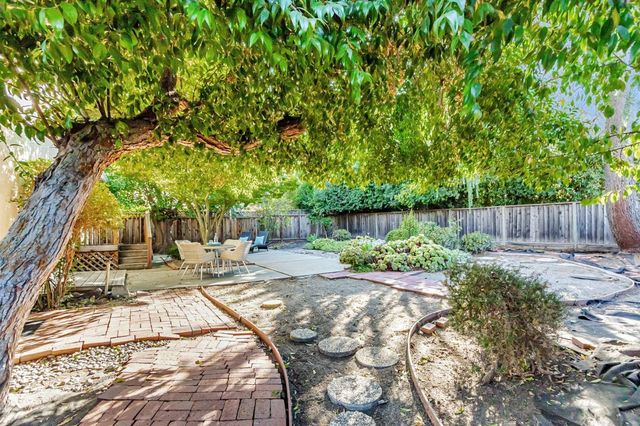 a view of backyard with wooden fence and a bench