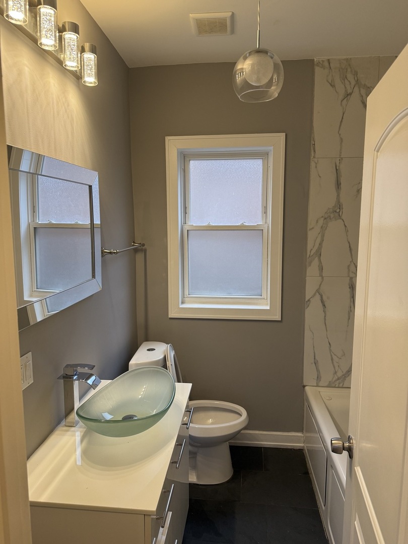 7806 South Rhodes Avenue Chicago, IL 60619 - Photo 15 of 29 a bathroom with a toilet sink and mirror