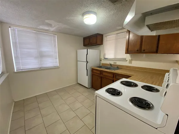a kitchen with a sink a stove a refrigerator and white cabinets