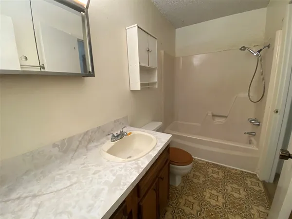 a bathroom with a granite countertop sink a toilet and shower