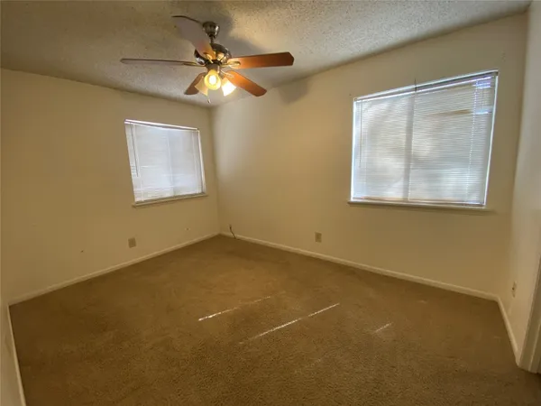 an empty room with a window and a fan