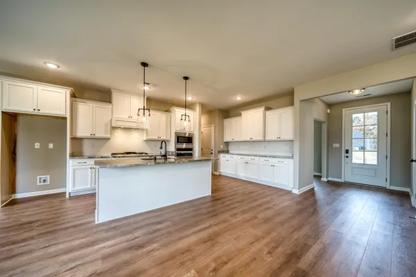 a kitchen with kitchen island granite countertop a stove a sink a center island and cabinets