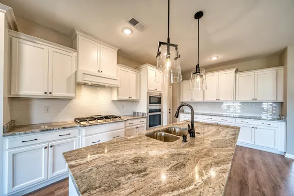 a kitchen with stainless steel appliances granite countertop a sink a stove and a refrigerator