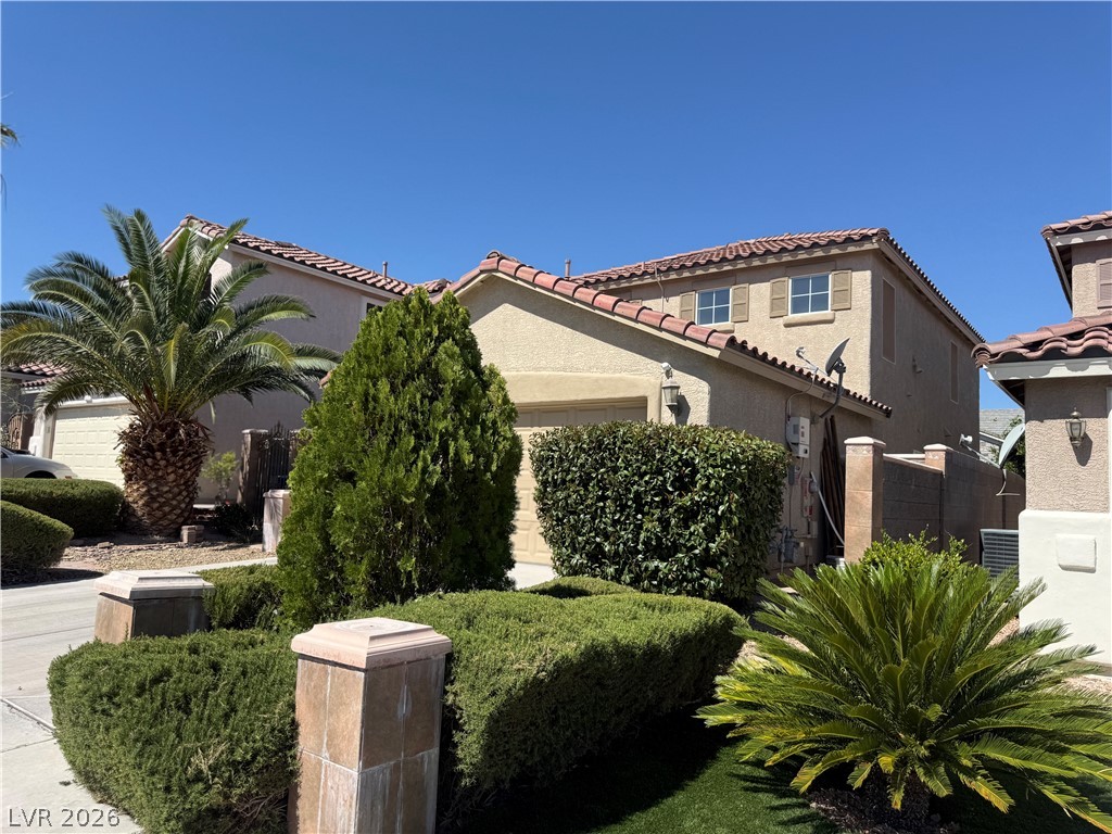 1141 Cathedral Ridge Street Henderson, NV 89052 - Photo 74 of 77 This residence showcases a Mediterranean-inspired roofline and manicured landscaping under a clear sky.