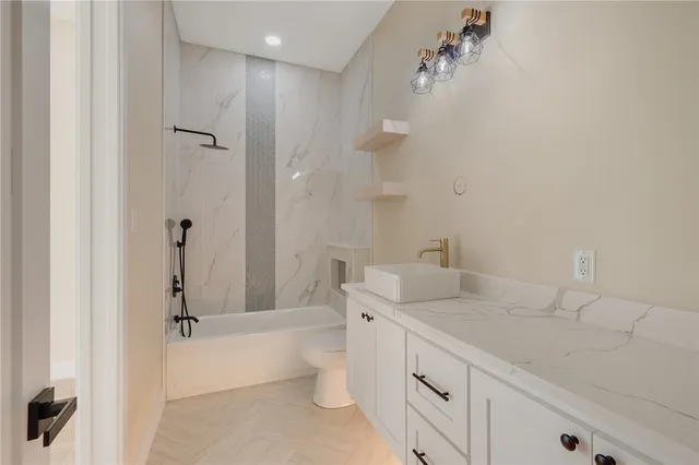 a bathroom with a granite countertop sink a toilet and shower