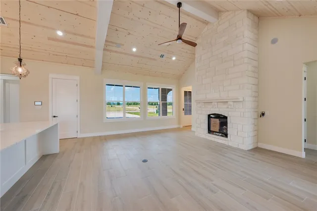 an empty room with wooden floor a fireplace and windows