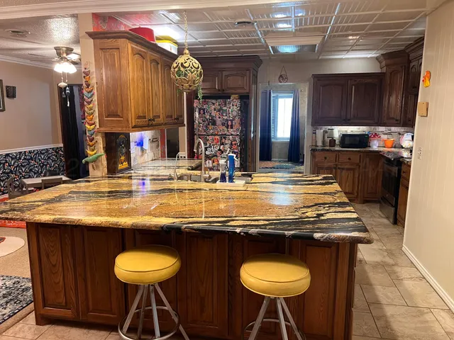 a utility room with stainless steel appliances kitchen island granite countertop a stove a sink and a refrigerator