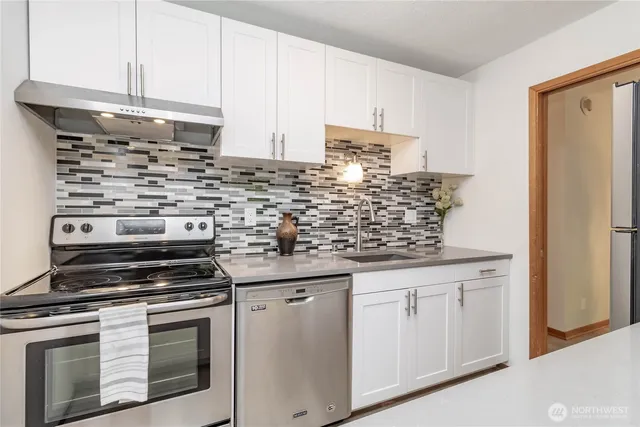 a kitchen with white cabinets and appliances