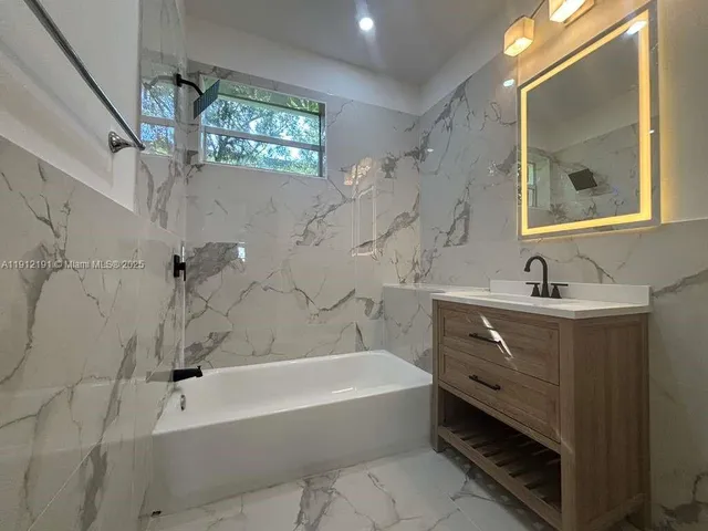 a bathroom with a tub sink double vanity and mirror