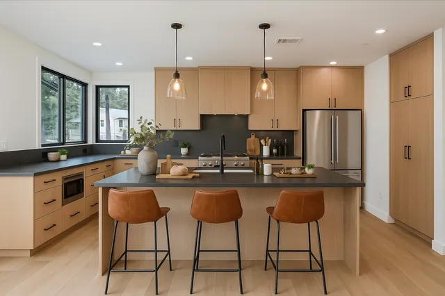 a kitchen with stainless steel appliances granite countertop a sink a stove a refrigerator and island with wooden floor