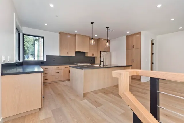 a large kitchen with granite countertop a large counter top a sink stainless steel appliances and cabinets