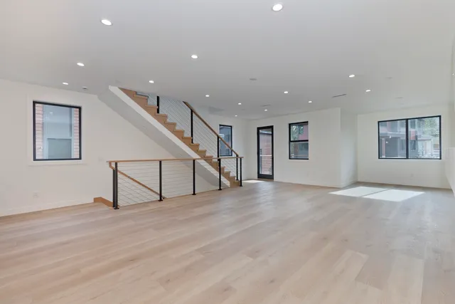 a view of an empty room with wooden floor and paintings