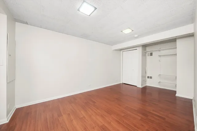 a view of an empty room with wooden floor and closet