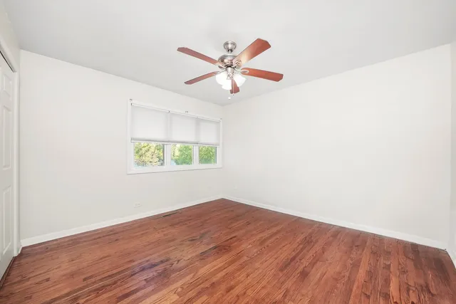 an empty room with wooden floor closet and fan