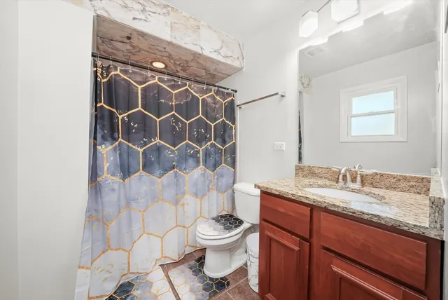a bathroom with a granite countertop sink toilet and shower