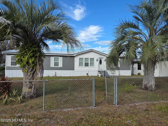 a view of a white house with a yard and potted plants