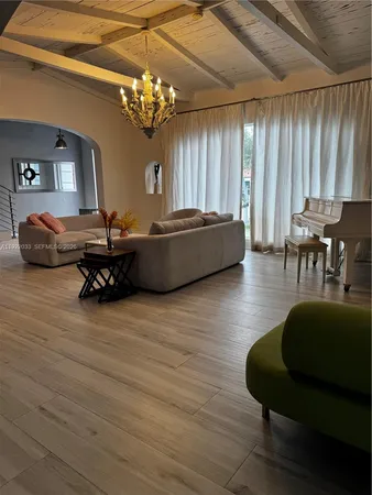 a view of a dining room and livingroom with furniture wooden floor a chandelier