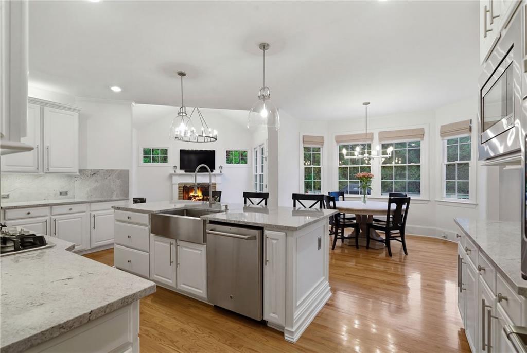 2058 Windermere Crossing Cumming, GA 30041 - Photo 17 of 75 a kitchen with stainless steel appliances granite countertop a stove top oven a sink dishwasher a dining table and chairs with wooden floor