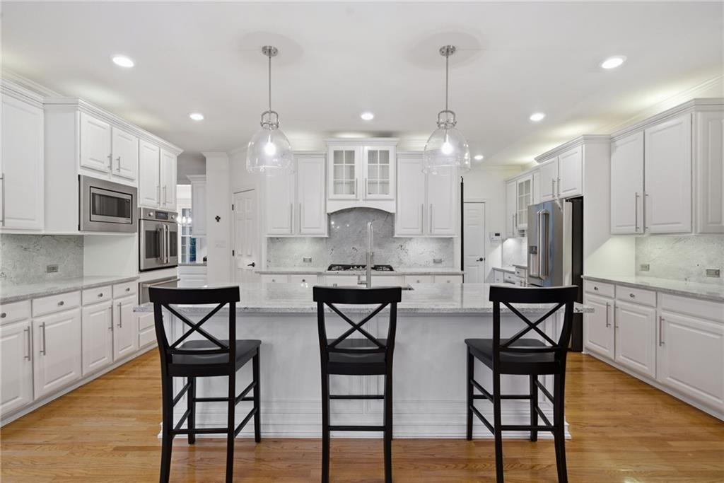 2058 Windermere Crossing Cumming, GA 30041 - Photo 19 of 75 a kitchen with stainless steel appliances granite countertop a kitchen island hardwood floor and chairs
