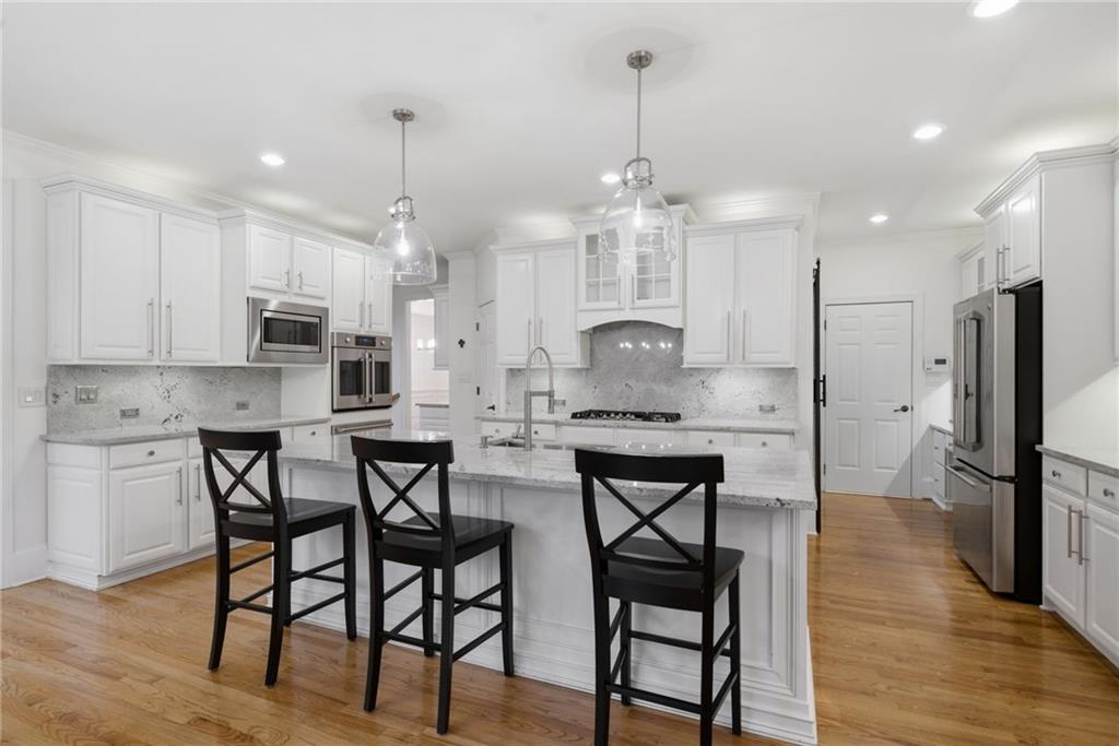 2058 Windermere Crossing Cumming, GA 30041 - Photo 20 of 75 a kitchen with stainless steel appliances kitchen island granite countertop a table chairs refrigerator and microwave