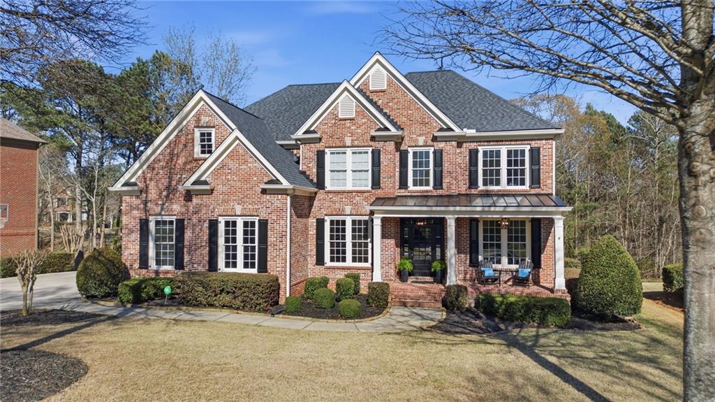 2058 Windermere Crossing Cumming, GA 30041 - Photo 2 of 75 a view of a brick house with large windows and a small yard