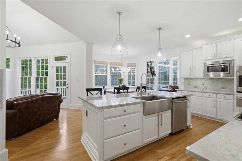 2058 Windermere Crossing Cumming, GA 30041 - Photo 22 of 75 a large kitchen with kitchen island granite countertop a stove a sink and dishwasher wooden cabinets with wooden floor