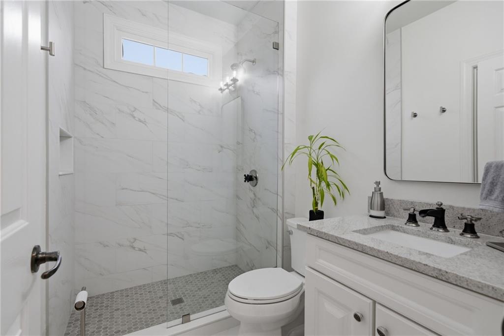 2058 Windermere Crossing Cumming, GA 30041 - Photo 28 of 75 a bathroom with a granite countertop toilet a sink and a shower