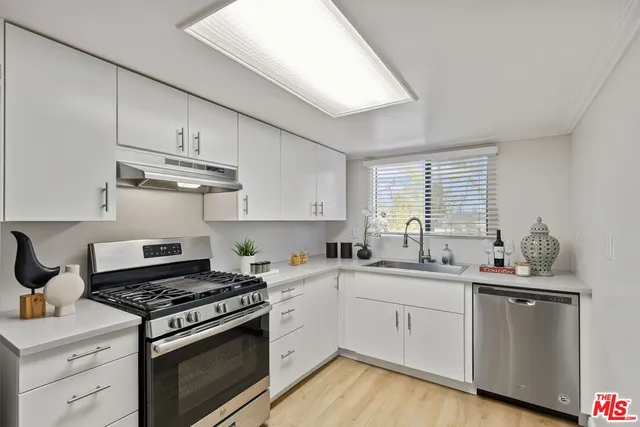 a kitchen with stainless steel appliances a sink a stove and cabinets
