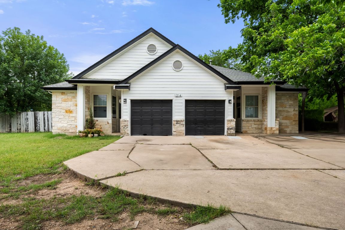 1214 Vargas Road, Unit A Austin, TX 78741 - Photo 1 of 25 View of front of home featuring stone siding, concrete driveway, an attached garage, and roof with shingles