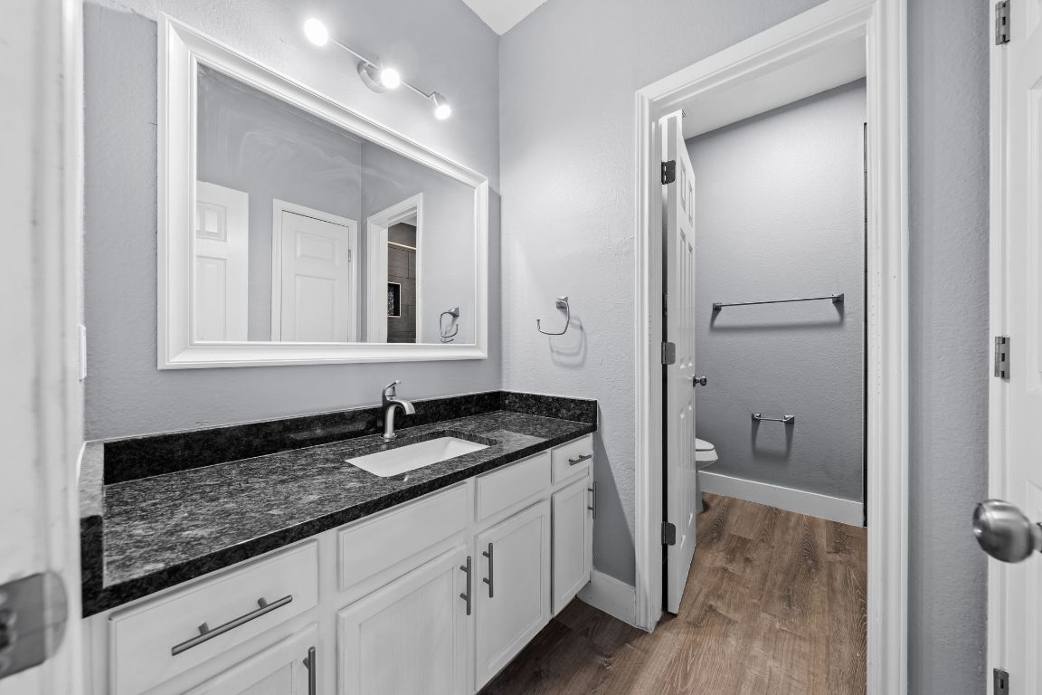 1214 Vargas Road, Unit A Austin, TX 78741 - Photo 18 of 25 Full bath with vanity, dark wood-style floors, and a textured wall