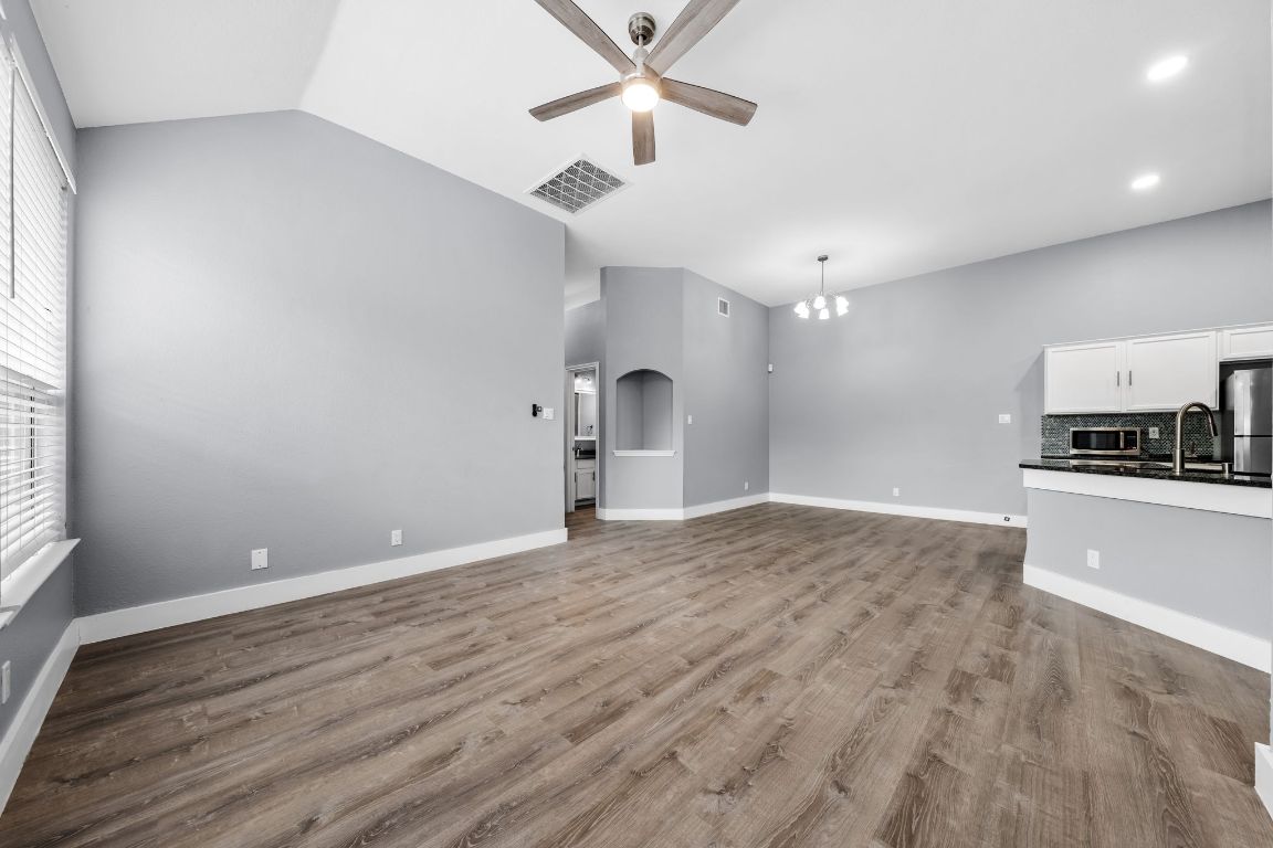 1214 Vargas Road, Unit A Austin, TX 78741 - Photo 7 of 25 Unfurnished living room with light wood-type flooring, ceiling fan, vaulted ceiling, and a chandelier