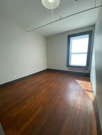 an empty room with wooden floor and windows