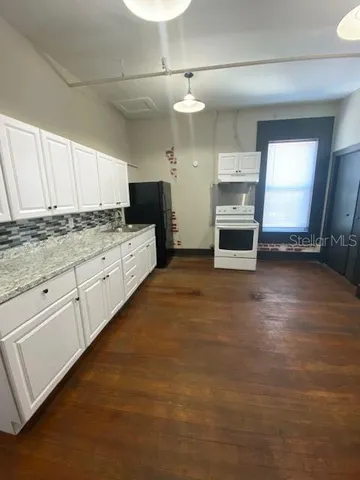 a kitchen with granite countertop a stove sink and cabinets