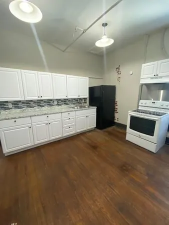 a kitchen with granite countertop a stove a sink and a refrigerator