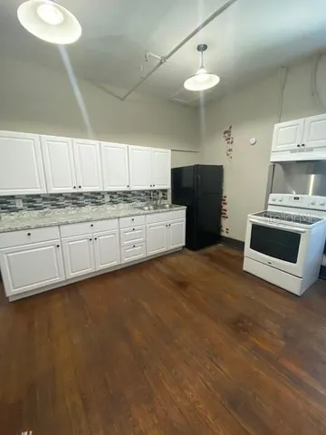 a kitchen with granite countertop a stove a sink and a refrigerator