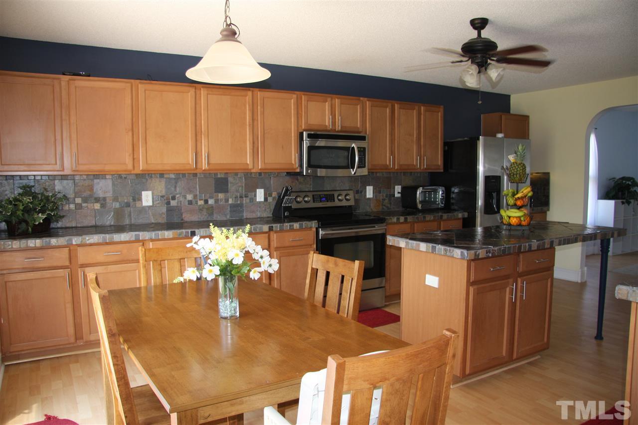 3136 Varcroft Road Knightdale, NC 27545 - Photo 11 of 23 a kitchen with stainless steel appliances granite countertop a refrigerator a stove a sink a dining table and chairs with wooden floor