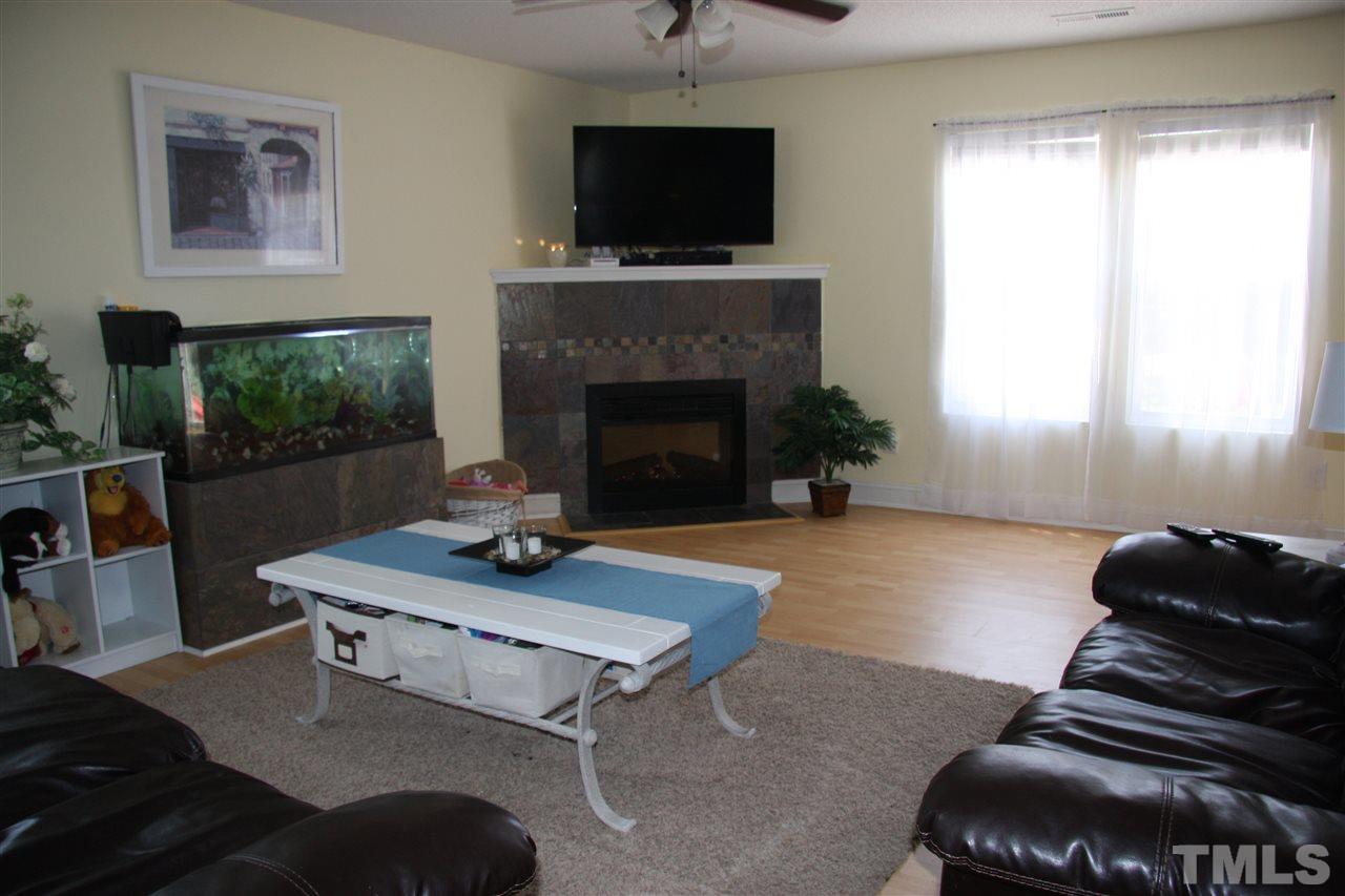 3136 Varcroft Road Knightdale, NC 27545 - Photo 7 of 23 a living room with furniture a flat screen tv and a fireplace