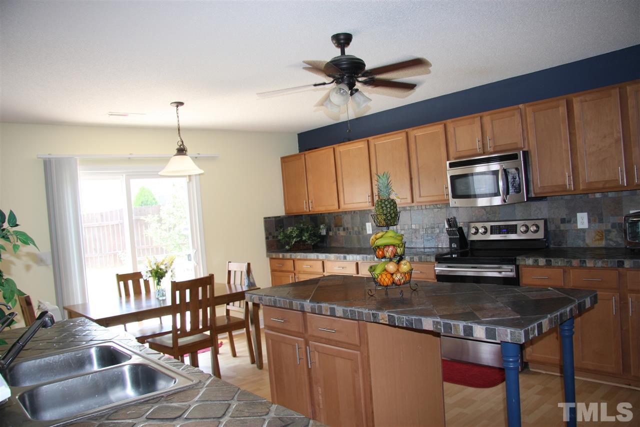 3136 Varcroft Road Knightdale, NC 27545 - Photo 8 of 23 a kitchen with stainless steel appliances granite countertop a stove top oven a refrigerator a sink and a dining table with white cabinets