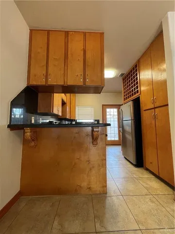 a kitchen with kitchen island granite countertop a refrigerator a stove and a sink