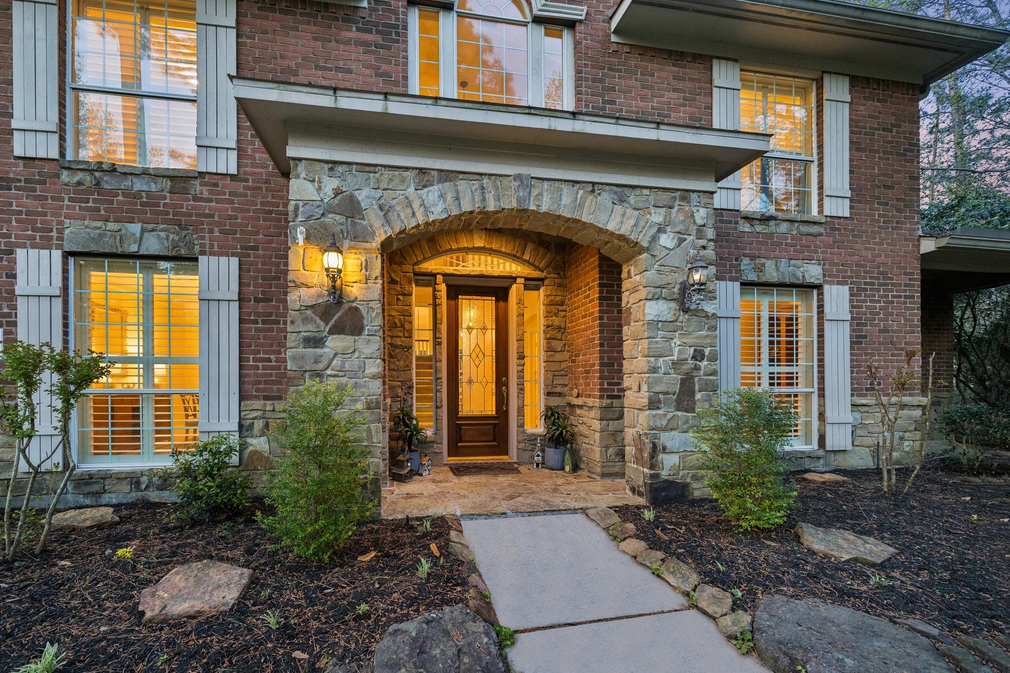 14530 Millhouse Road Pinehurst, TX 77362 - Photo 4 of 46 Inviting front entry with stone-accented archway, warm lighting, and a welcoming covered porch that sets the tone for the home’s timeless design.