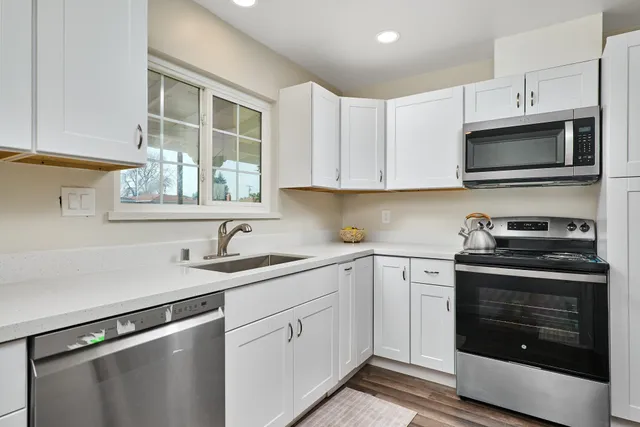a kitchen with cabinets stainless steel appliances a sink and a window