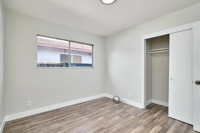 a view of an empty room with wooden floor and a window