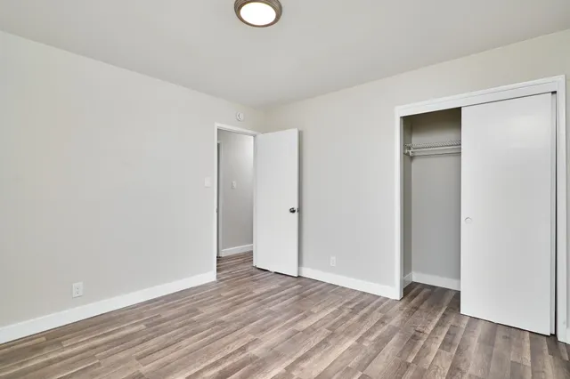 a view of an empty room with wooden floor and closet