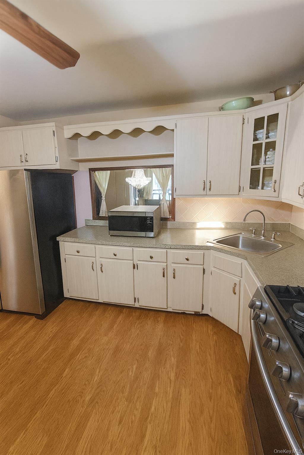 598 Shepherd Avenue Brooklyn, NY 11208 - Photo 4 of 8 Kitchen featuring appliances with stainless steel finishes, light countertops, light wood-type flooring, glass insert cabinets, and white cabinetry
